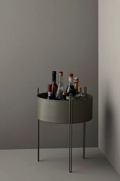 a round table with bottles and glasses on it in front of a gray wall,