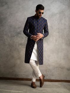 Embroidered Jamawar Blue Sherwani for Wedding is our blue sherwani that gives an air of regality with its stunning panel work with hints of golden printed work and scattered with champagne mixed printed to balance the tones. Sherwani: Elegant Sherwani in Blue color is floral printed sherwani. Blue Jamawar sherwani with a golden printed base and with Embellished cuff is looking elegant. Mens Sherwani fabric is jamawar. A labor of love that took our artisans a minimum of 300 hours to create. Black Dark Blue Sherwani Groom, Indian Wedding Sherwani Groom Outfit, Embroidery Sherwani For Men, Sherwani For Men Wedding Guest, Indian Wedding Groom Outfits, Indian Men Sherwani, Blue Sherwani Groom, Blue Sherwani For Men, Sherwani For Men Wedding Pakistani