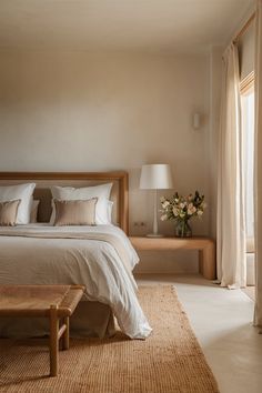 a bedroom with a large bed and two tables in front of the window that are open