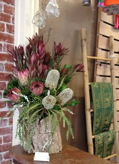 a vase filled with flowers sitting on top of a table next to a brick wall