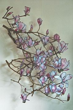 a vase filled with pink flowers sitting on top of a wooden table next to a wall