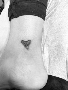 a black and white photo of a person's foot with a small triangle tattoo on it