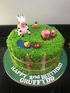 a birthday cake decorated with farm animals and grass