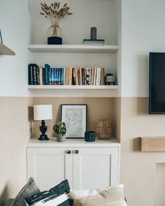 a living room with bookshelves, shelves and a television on top of it