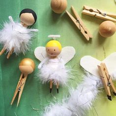 several wooden pegs and angel dolls on a green surface with white feathered decorations