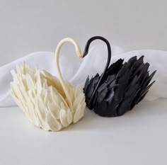 two black and white swan sculptures sitting next to each other on top of a table