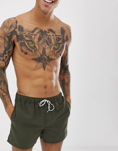 a man with tattoos on his chest and arms is smiling at the camera while standing in front of a white background