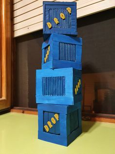 three cardboard boxes stacked on top of each other in the shape of a house with yellow and blue decorations