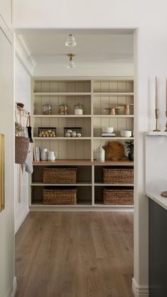 a kitchen with white walls and wooden floors is seen from the hallway to the dining room