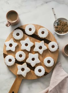 small cookies are arranged on a wooden platter next to two cups and spoons