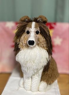 a brown and white dog figurine sitting on top of a wooden table next to a pink pillow