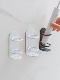 two white and black wall mounted toothbrush holders next to each other on a marble surface