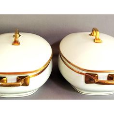 two white and gold covered dishes sitting next to each other