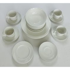 an assortment of white dishes, cups and saucers