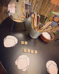 a table topped with lots of books and pencils next to a cup filled with pens