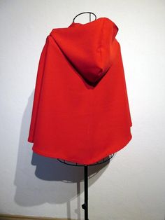 a red hooded jacket on a mannequin stand in front of a white wall