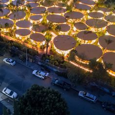 an aerial view of several large umbrellas lit up at night in front of a parking lot