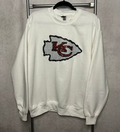 Kansas City Chiefs Sweatshirt with Feaux Sequin Logo Patch on Front of Sweatshirt. Very Comfy and ready to wear anytime!!!! White Long Sleeve Tops For Fan Gear, White Tops With Team Spirit For Fall, White Tops For Fall With Team Spirit Style, White Tops With Team Spirit For Winter, White Crew Neck Top For Fan Gear, Fall Fan Gear T-shirt With Crew Neck, Fall Crew Neck T-shirt For Fan Gear, White Tops For School Spirit In Fall, White Tops For Fall School Spirit