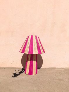 a pink and white lamp sitting on the ground