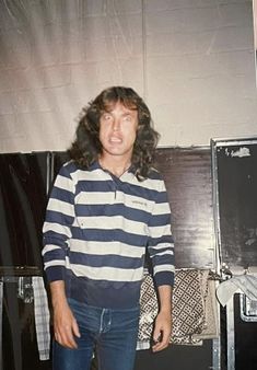 a man in striped shirt standing next to two speakers and an old fashioned record player