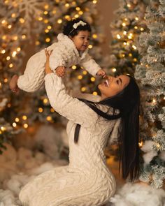 a woman holding a baby in front of a christmas tree