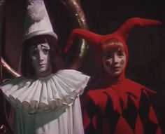 two people in costumes standing next to each other with horns on their heads and hands behind them