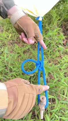 a person holding onto a blue rope in the middle of some grass with one hand on it