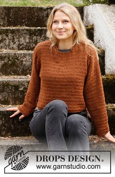 a woman sitting on some steps wearing a brown sweater