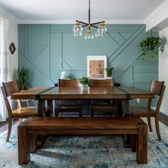 a dining room table with chairs and a bench in front of it, against a blue wall