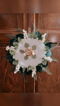 a white and green flower arrangement sitting on top of a wooden door