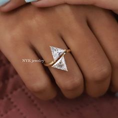 a woman's hand wearing a gold ring with a white diamond in the middle