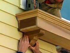 a man is working on the side of a house with wood trimming and nails