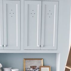 a kitchen with blue walls and white cupboards in the corner next to a shelf