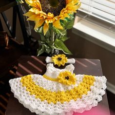 a crocheted dress and sunflowers on a table