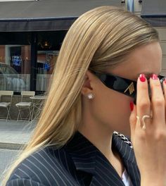 a woman with red nails is looking through her sunglasses