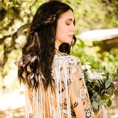 a woman with long hair wearing a dress and holding flowers