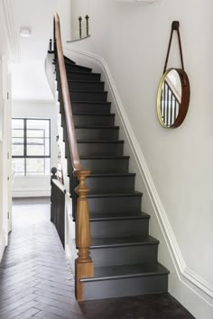 the stairs are black and white in this hallway, with a mirror on the wall