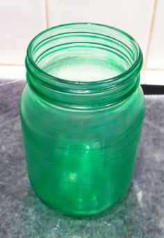 a green glass jar sitting on top of a counter