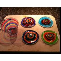 six colorful glass plates sitting on top of a wooden tray