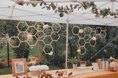 the table is set up for an outdoor party with honeycombs hanging from the ceiling