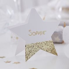 a star shaped place card on a table with confetti and glasses in the background