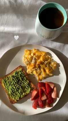 a white plate topped with toast and fruit next to a cup of coffee