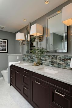 a large bathroom with two sinks and mirrors on the wall next to it's toilet