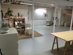 an empty room with white walls and lights on the ceiling, some wooden tables and chairs