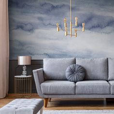 a living room with a gray couch and gold chandelier