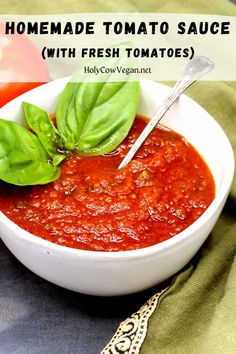 homemade tomato sauce with fresh tomatoes and basil in a white bowl on a green cloth