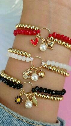 several different bracelets with charms and beads on the wrist, all in gold plated metal