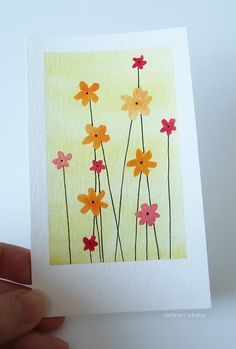 a hand holding up a card with flowers painted on it