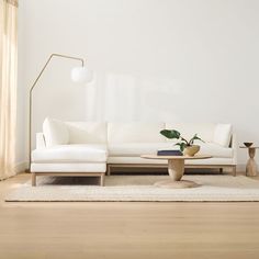 a living room with a white couch, table and lamp on the wall next to it