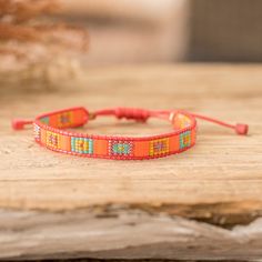 an orange beaded bracelet sitting on top of a wooden table